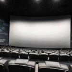 Sala de cinema com tela grande e assentos vazios, remetendo aos filmes de Resident Evil