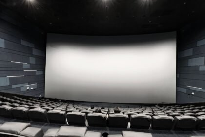 Sala de cinema com tela grande e assentos vazios, remetendo aos filmes de Resident Evil
