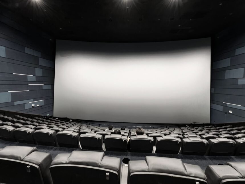 Sala de cinema com tela grande e assentos vazios, remetendo aos filmes de Resident Evil