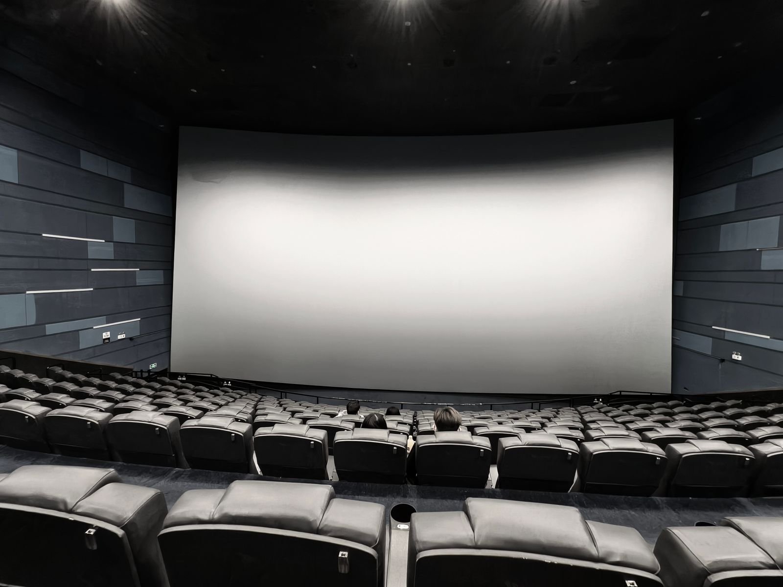 Sala de cinema com tela grande e assentos vazios, remetendo aos filmes de Resident Evil