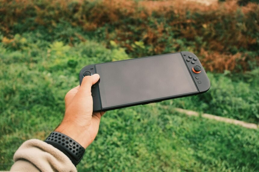Mão segurando console portátil ao ar livre, como o Nintendo Switch 2